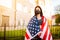 Girl in protective black medical mask wrapped in american flag . Pandemic in quarantine city. Preventing the spread of the