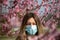 Girl with protective mask in front of blooming tree