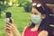 Girl in protective mask holding a smartphone. teen girl siting on bench in green park with mobile phone. First stage of loosening