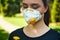 Girl in a protective mask smiles with dandelion in hand, COVID-19 coronavirus prevention, nature protection, quarantine time