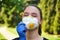 Girl in a protective mask smiles with dandelion in hand, COVID-19 coronavirus prevention, nature protection, quarantine time