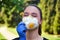 Girl in a protective mask smiles with dandelion in hand, COVID-19 coronavirus prevention, nature protection, quarantine time