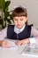 A girl pupil  sits at  a desk in the classroom and reads a book