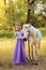 Girl in purple dress with wreath of a unicorn in hair hugging white unicorn horse. Dreams come true. Fairy tale