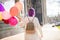 Girl with purple hair with colored balloons standing turn her back