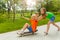 Girl pushes boy with arms apart on skateboard