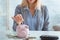Girl puts coin piggy bank, near cash and calculator