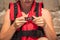 Girl putting on red life jacket on beach. Female hands fastens plastic buckle clasp of life vest. Safety during water sports