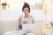 Girl in pyjama having cereal using laptop