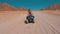 Girl on a quad bike rides through the desert of Egypt on background of mountains