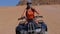 Girl on a Quad Bike Rides through the Desert of Egypt on Background of Mountains. Slow Motion