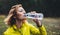 Girl quenches thirst after fitness. Smile person drinking water from plastic bottles relax after exercising sport outdoors