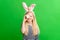 Girl in rabbit bunny ears on head on green studio background. Cheerful crazy smiling happy child. Easter painting eggs