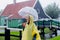 Girl in rain suit with umbrella stay on bridge with dutch house