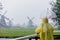 Girl in rain suit with umbrella stay on bridge with dutch mills