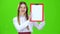 Girl raises a red tablet with paper . Green screen