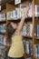 Girl reaching for a book in library