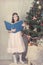 Girl reading book around Christmas tree