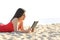 Girl reading an ebook or tablet on the beach
