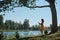 Girl reads book by lake. Education outside city