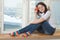 Girl with red apple sits on a window-sill