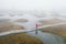 Girl in red cloak and boots, misty autumn morning. Aerial shot of Yelnya swamp.