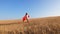 Girl in red cloak plays superhero in a field with wheat. Slow motion.
