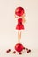 Girl in red dress with Christmas ornament balls  on bright background. Minimal party Christmas or New Year festive idea