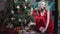 Girl in red dress has fun stacking presents under the Christmas tree
