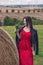 Girl in a red dress near a round bale of straw