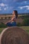 Girl in a red dress near a round bale of straw