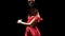 Girl in red dress performs elegant movements with her hands in dance. Black background