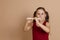 Girl in red dress play melody on flute with pleasure, blowing air into duct, beige background. Learn to play woodwind