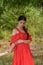 A girl in a red dress is standing on a wooden bridge in the forest