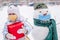 girl with red gift box and snowman in protective medical mask outdoors in winter against backdrop of snowdrifts and