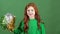 Girl red hair celebrating saint patrick`s day green wall background holding cheering pom poms