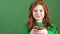 Girl red hair celebrating saint patrick`s day green wall background holding lucky pot