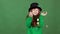 Girl red hair celebrating saint patrick`s day green wall background standing throwing gold