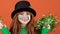 Girl red hair celebrating Saint Patrick`s Day orange background holding pom poms