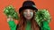 Girl red hair celebrating saint patrick`s day orange background shaking pom poms