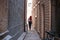 Girl with red hair in dress passing trough city tiny shallow street passage