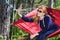 Girl in red hammock, woods