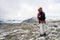 Girl with red hooded jacket and backpack are hiking in snow covered mountains with beautiful scenic landscape view and foggy weath