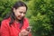 Girl in a red jacket in the Park listening to music with headphones earbuds with a smartphone in hand