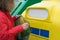 A girl in a red jacket pulls out a plastic bottle from a garbage bag to throw in a special container, sorting garbage