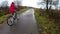 A girl in a red jacket rides a white Bicycle on an asphalt road