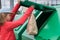 Girl in a red jacket throws a paper bag into the trash tank