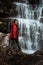 Girl in red jacket by the waterfall