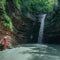 Girl in red looks at the waterfall Maiden spit on the stream Rufabgo, Adygea, Russia