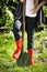 Girl in red rubber boots holding leg on shovel at garden
